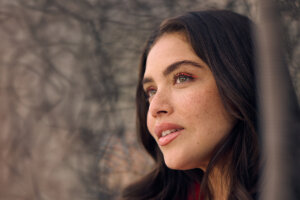 A woman is gazing into the distance against a brown background, showing off her lash lift and tint results.