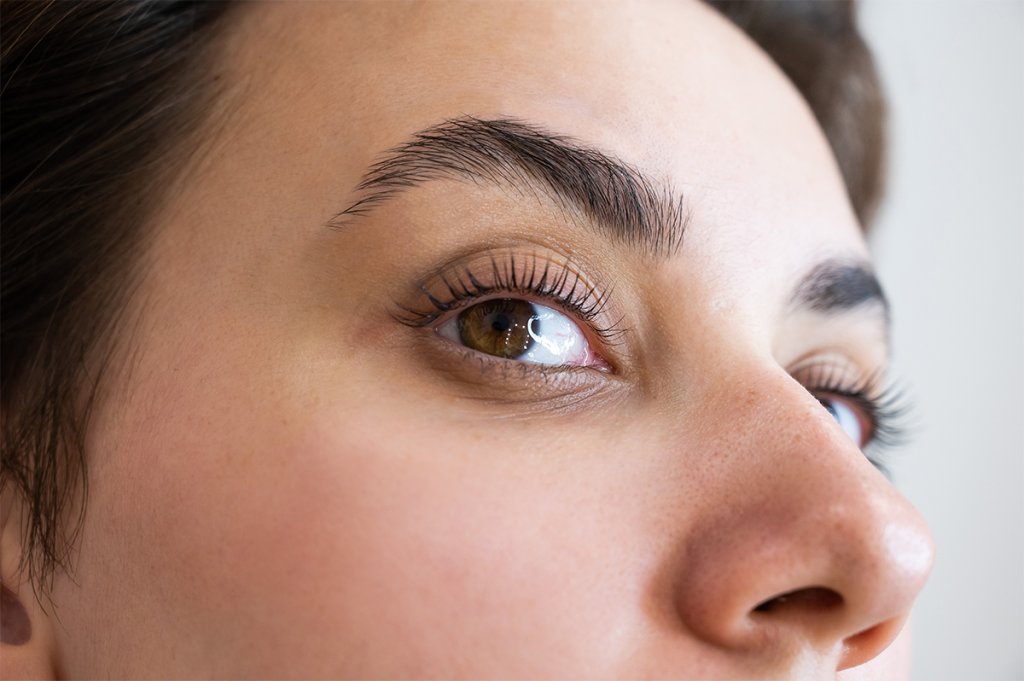 Close-up view of a woman's eye and brows, highlighting natural eyelashes that have been treated with a lash lift.