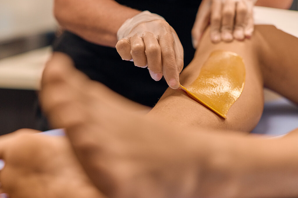 A Cerologist performing a leg waxing service on a client.