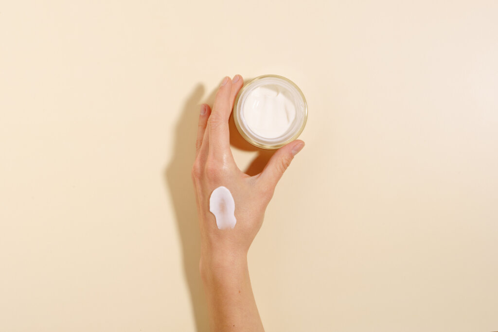 Hand holding a jar of moisturizer.