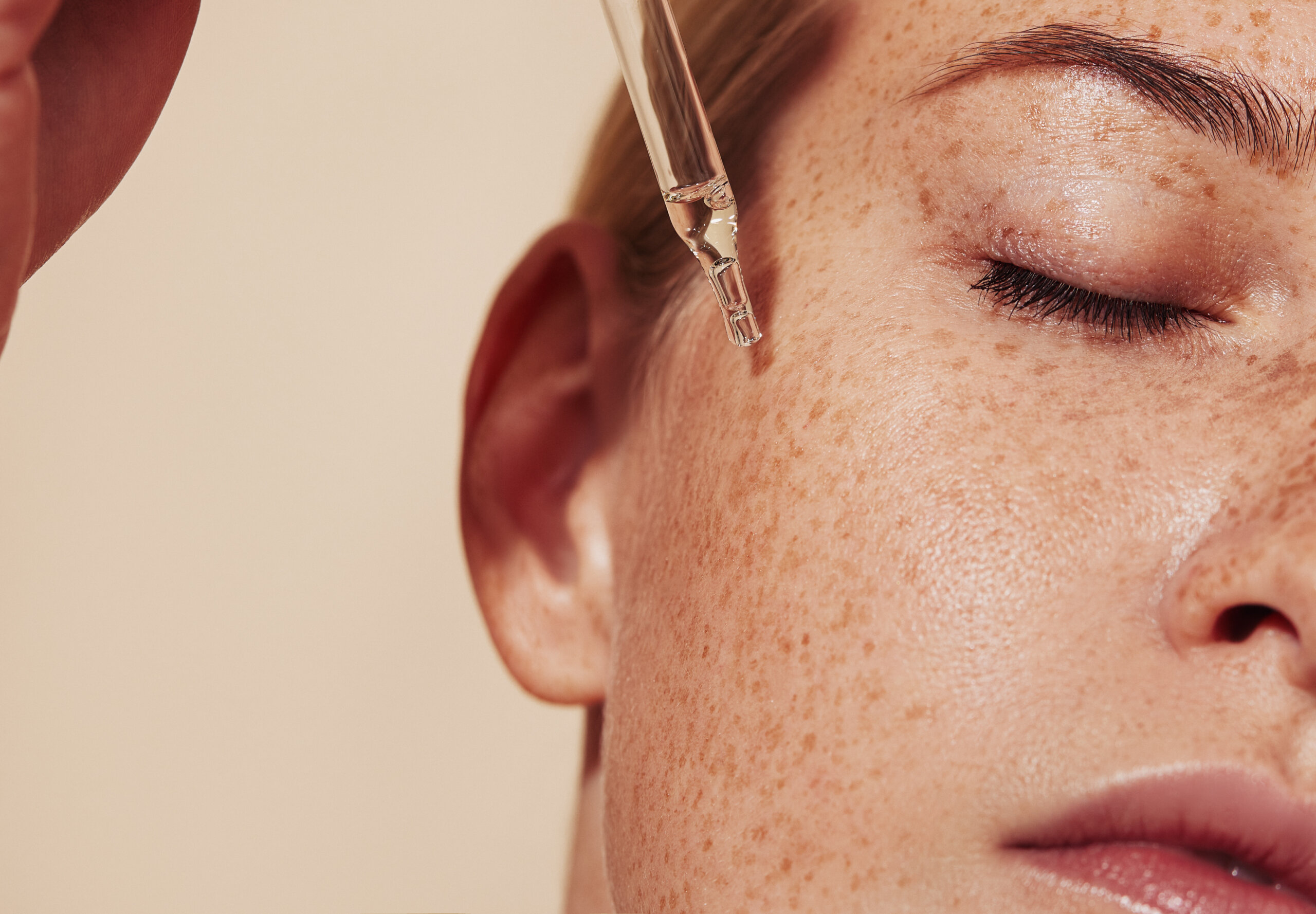 Woman applying facial oil to her face as part of her skincare routine order.