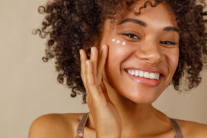 A woman is applying skincare products to her face.
